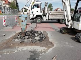 Bagger mit Hydraulikhammer beim Aufbrechen einer Asphaltfläche