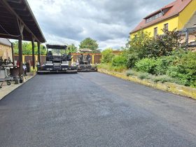 Zwei Straßenfertiger nebeneinander auf einer frisch eingebauten Asphaltfläche